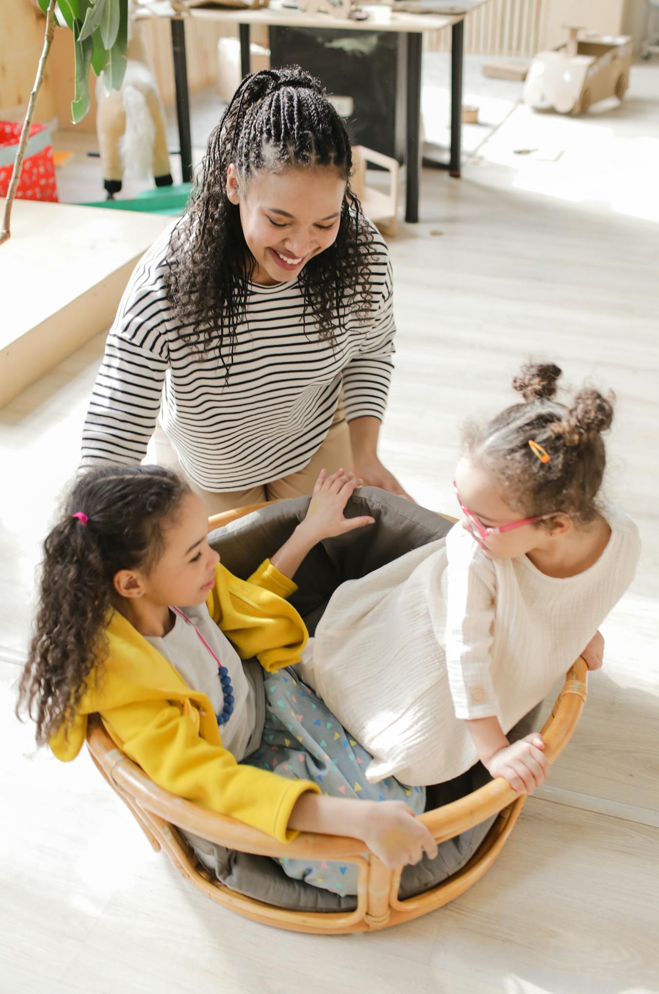 Joyful teacher engaging with children in a playful classroom setting.